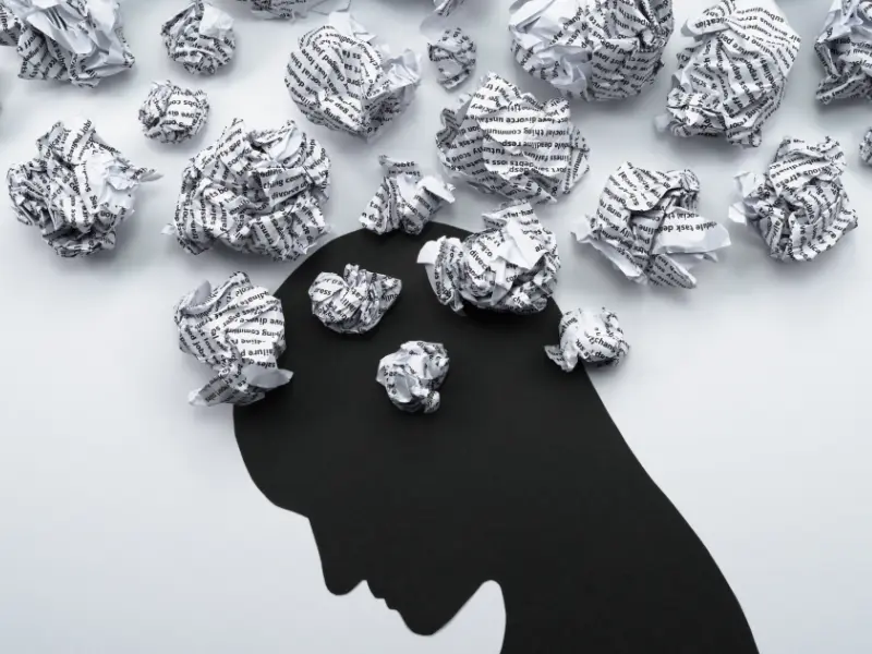 Image of a person with crunched up papers representing messy thoughts, anxiety and depression