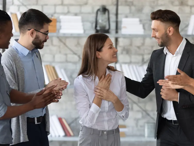 A group of colleagues looking happy and cheering up one of their colleagues.