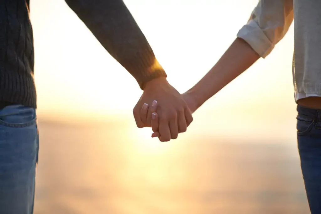 A couple holding hands on a beach at sunset