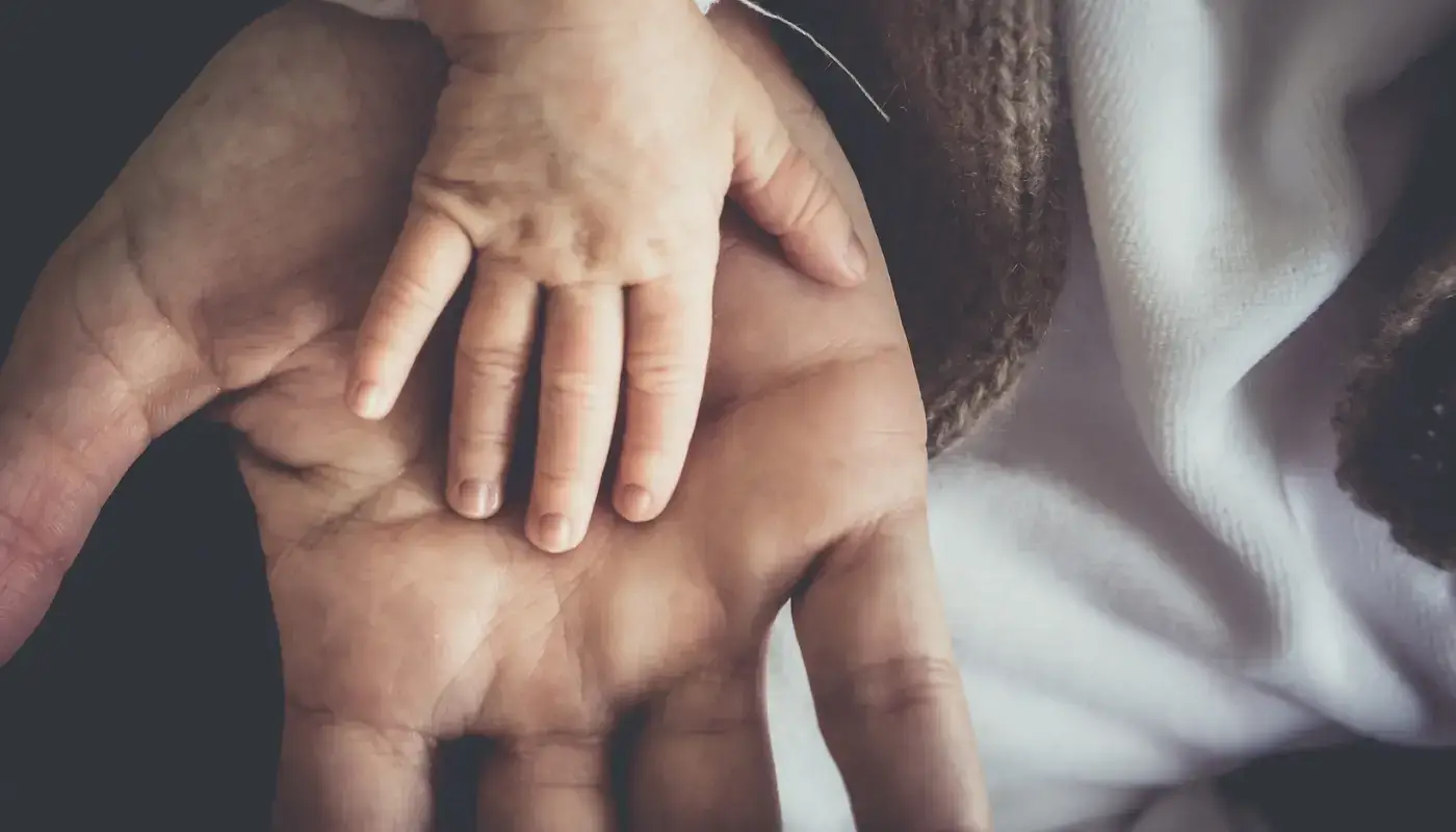 A baby hand on an adult hand, representing the inner child and current adult