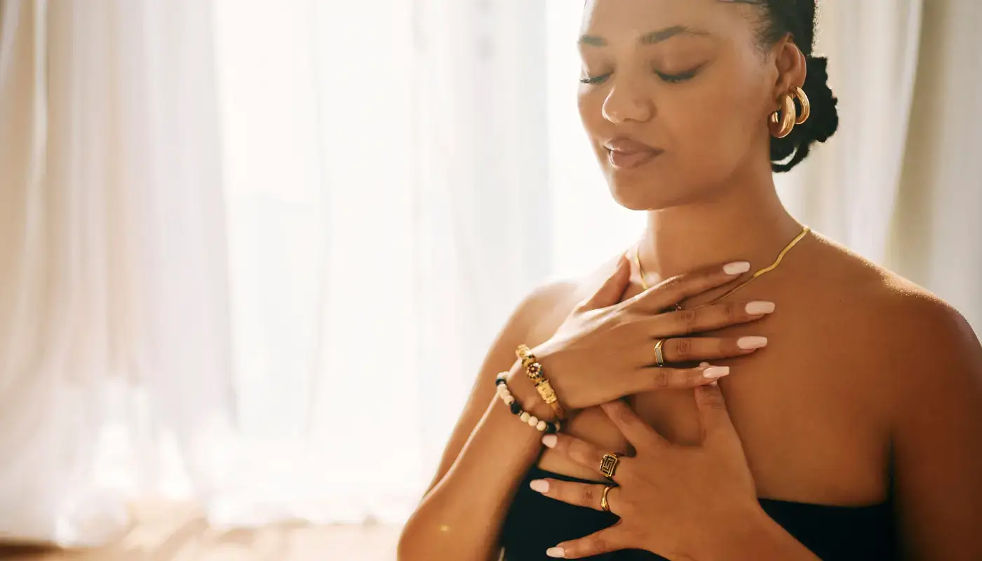 A woman looking relaxed, breathing with her hands on her chest