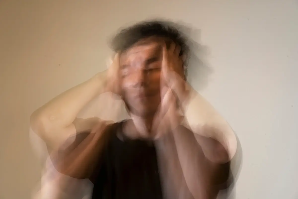 Blurry picture of a man holding his head in his hand, looking stressed